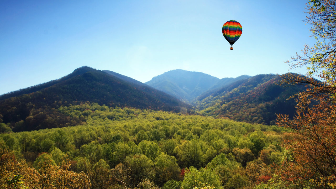 hot air balloon flying over smokey mountains